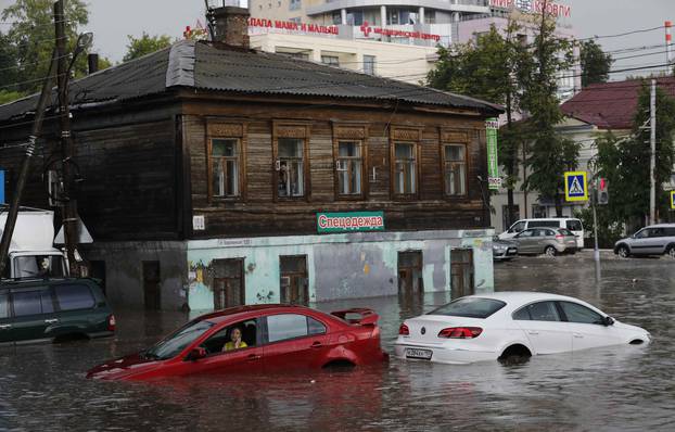 A woman uses her phone as she sits in the car at the flooded street in Nizhny Novgorod