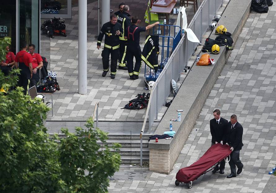A bag on a stretcher is wheeled away from a tower block that was severely damaged by a serious fire, in north Kensington, West London