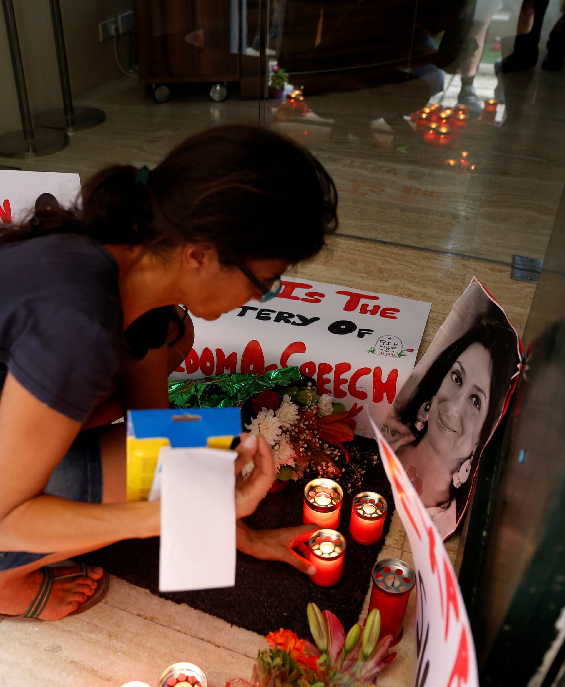 Activists place photos of assassinated anti-corruption journalist Caruana Galizia together with flowers, candles and protest posters, in the entrance of Malta's Ministry of Justice in Valletta