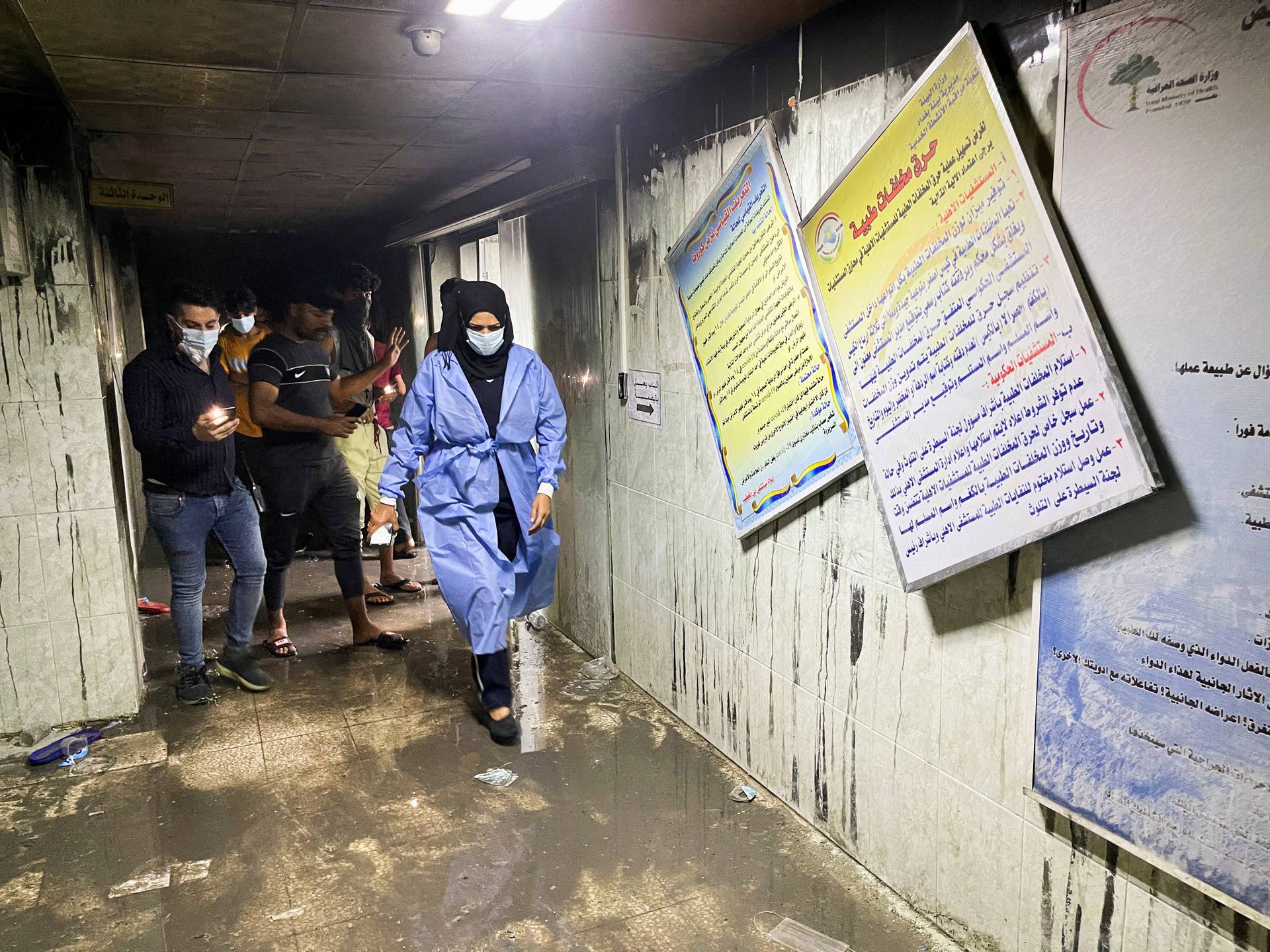 People and medical staff members walk at Ibn Khatib hospital after a fire caused by an oxygen tank explosion in Baghdad