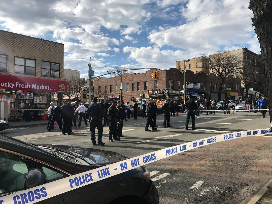 Police officers stand behind a cordon tape at the scene of a shooting in Brooklyn, New York