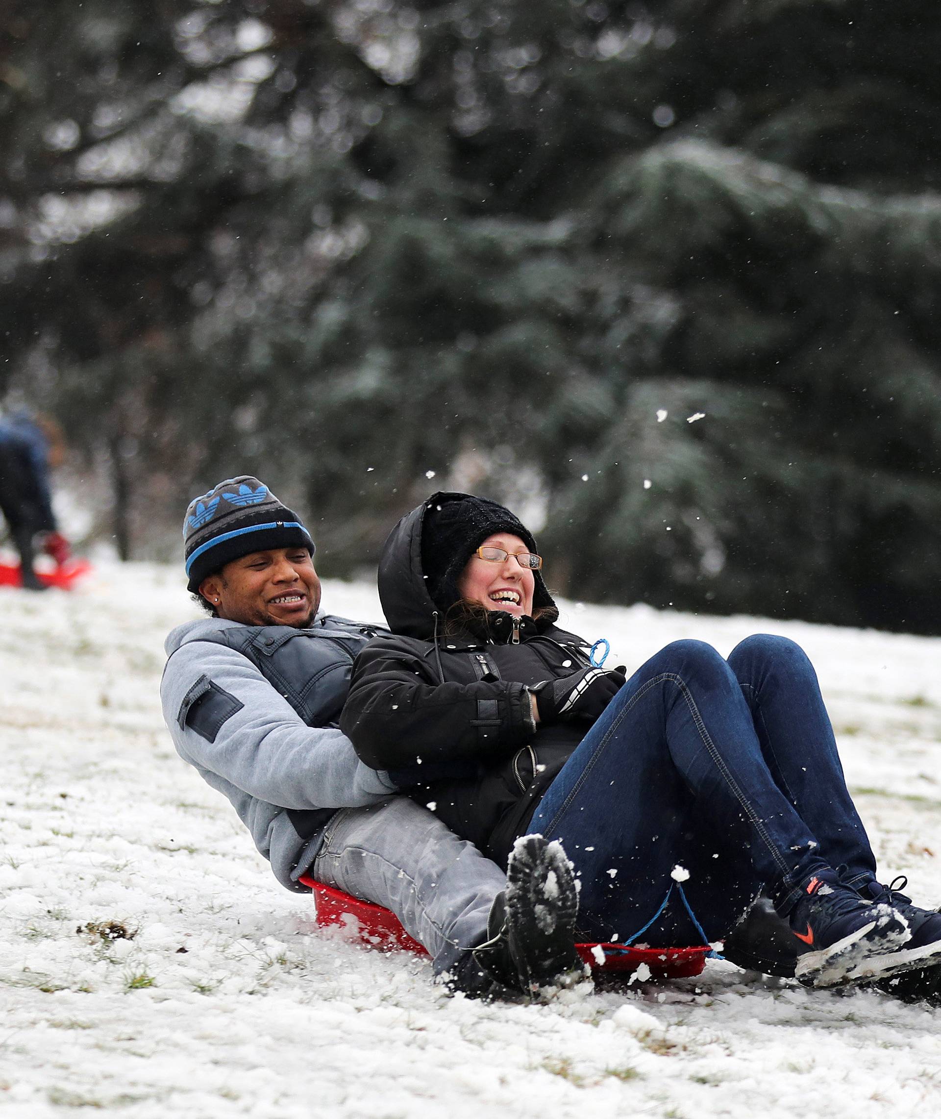 People sled down a hill in the snow in Greenwich Park, London