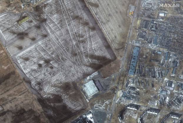 A satellite image shows a multispectral view of craters in a field and damaged buildings, in the western section of Mariupol