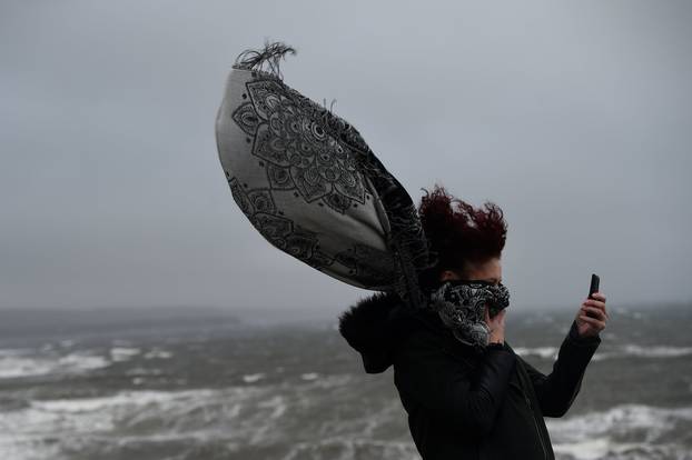 A woman takes a picture during storm Ophelia in the County Clare town of Lahinch