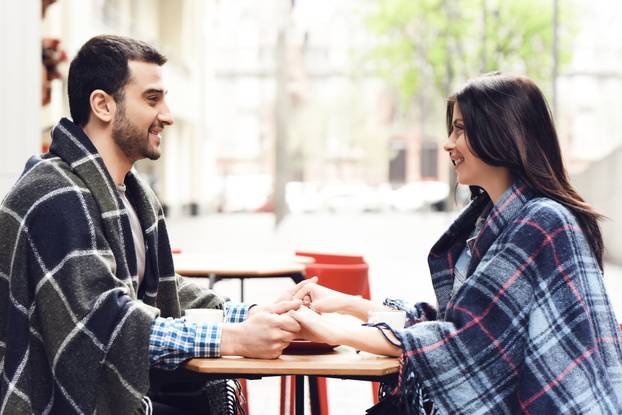 Loving couple in rugs sits at table.
