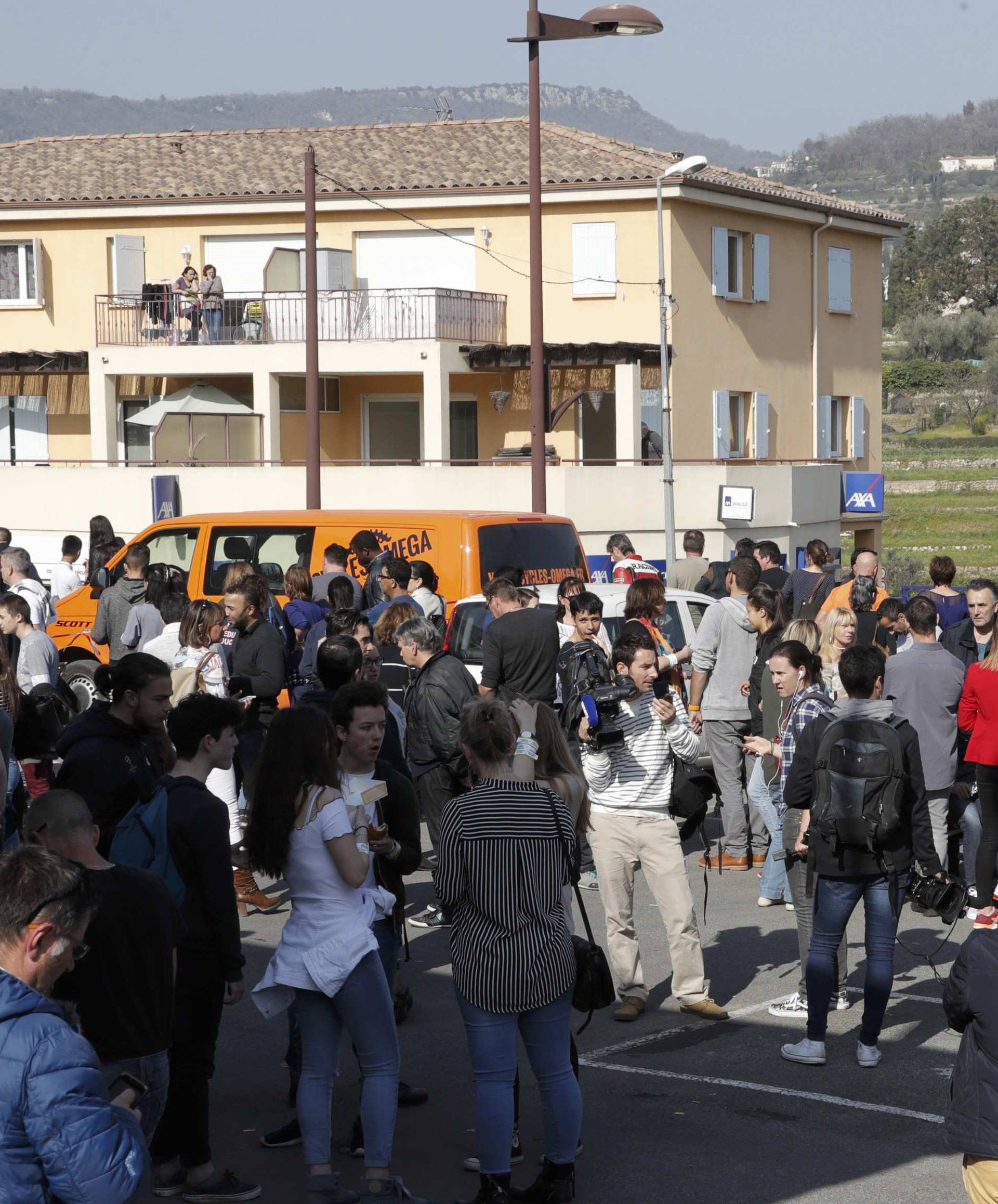 High school students stand near the Tocqueville high school after a shooting incident injuring at least eight people, in Grasse, southern France