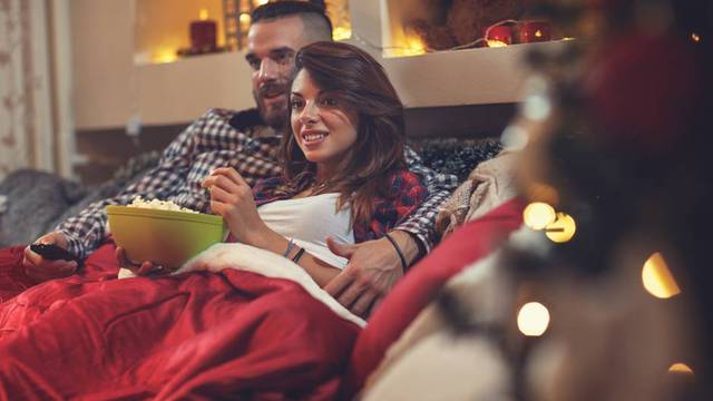 Young,Man,And,Woman,In,Bed,Watching,Tv,And,Eating