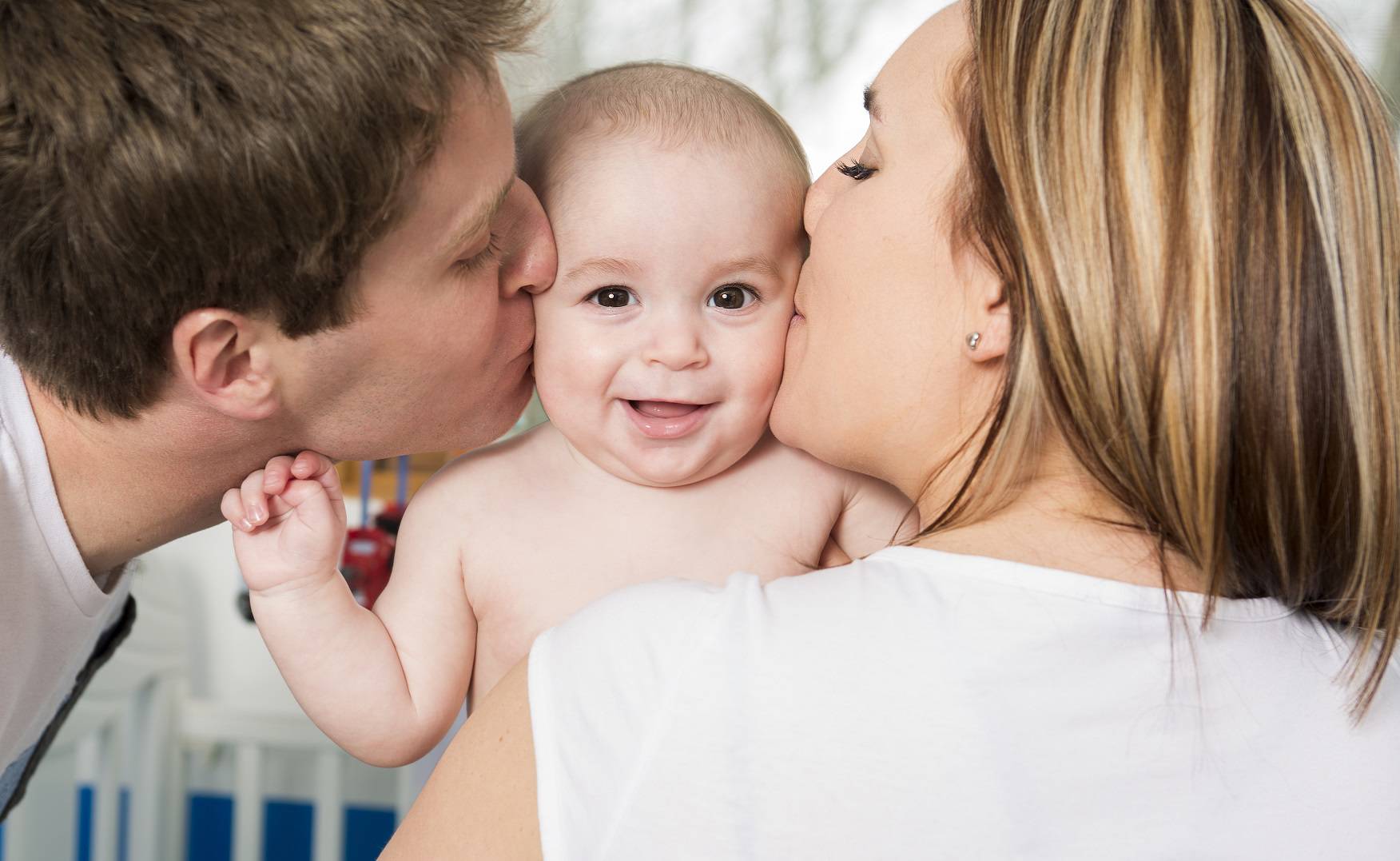 Closeup portrait of young parents kissing beautiful newborn son