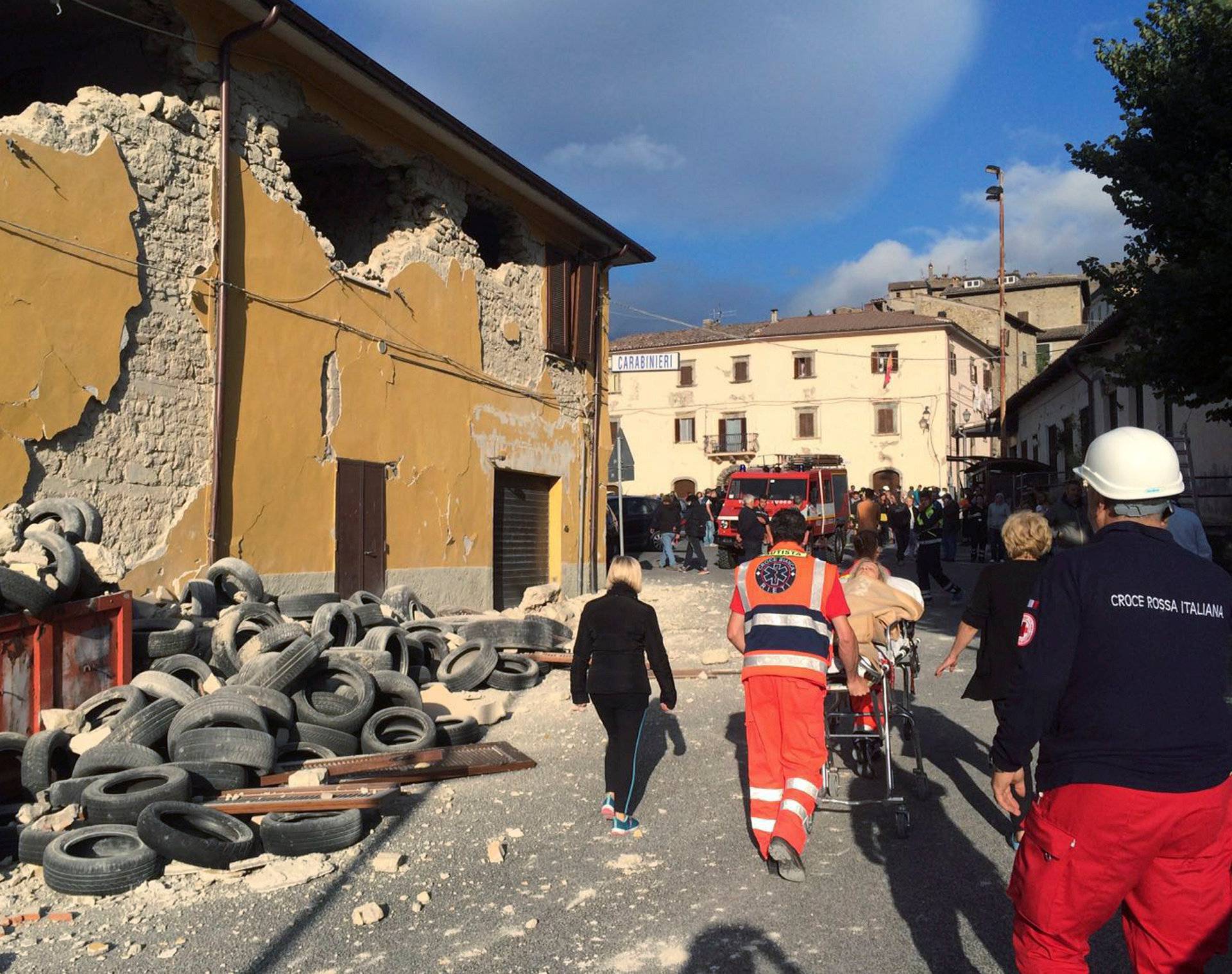 Rescuers and people walk along a road following an earthquake in Accumoli di Rieti, central Italy