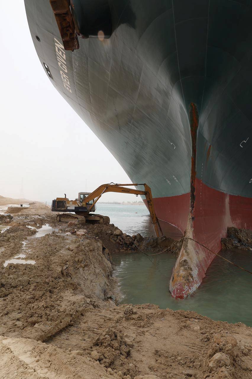 An excavator attempts to free stranded container ship Ever Given, one of the world's largest container ships, after it ran aground, in Suez Canal