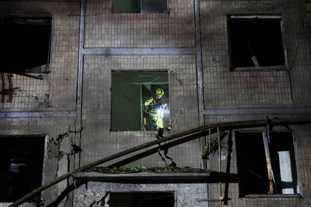 Firefighters work at the site of an apartment building hit by a Russian missile strike in Kyiv