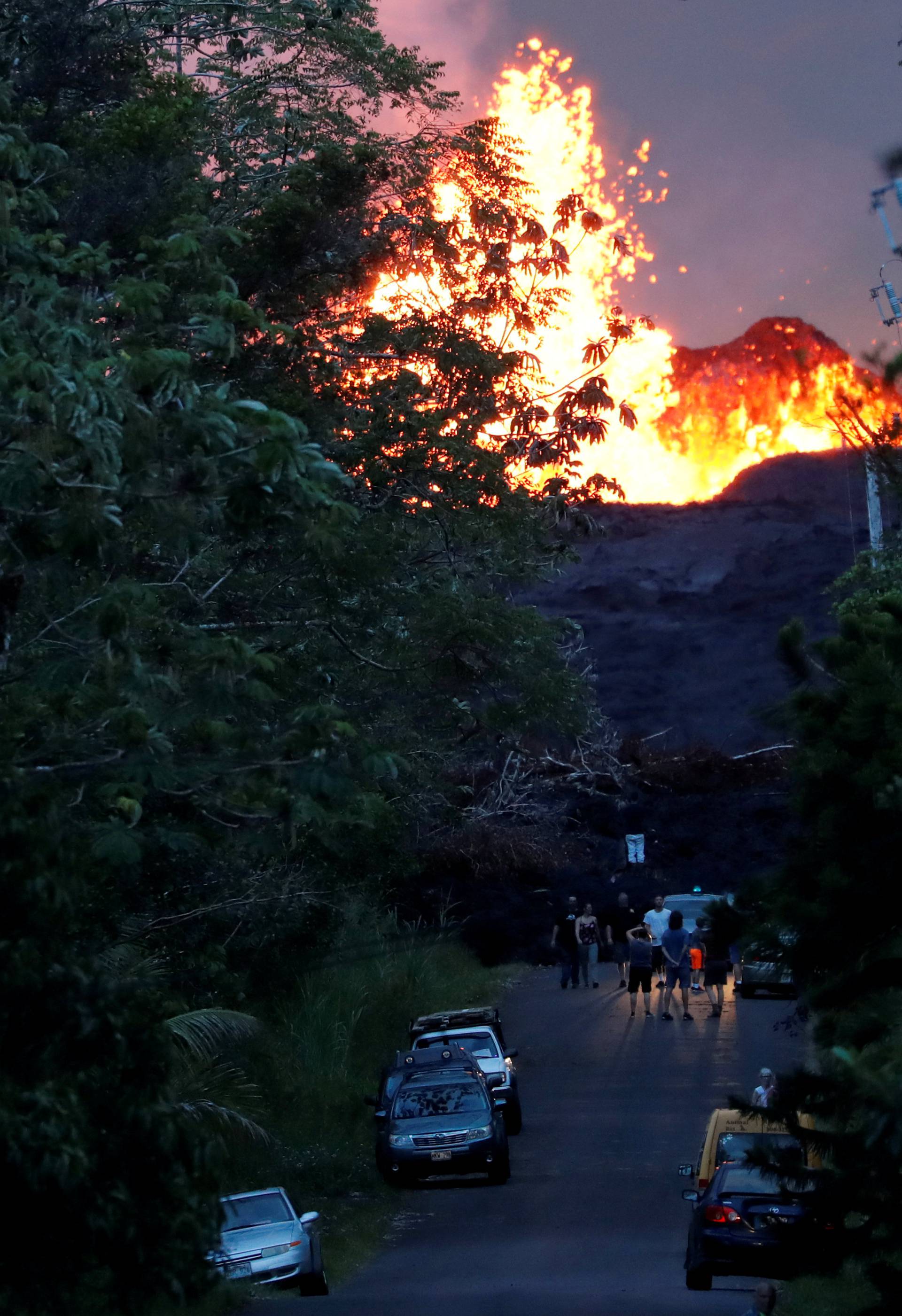 Onlookers gather at the foot of the lava bed, as a lava shoots molten rock into the air, in the Leilani Estates near Pahoa, Hawaii