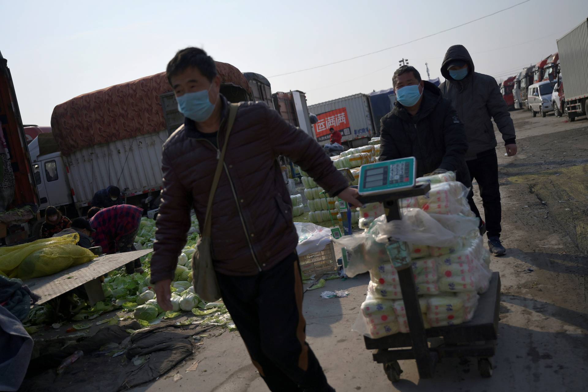 Men wearing face masks pull a cart carrying vegetables at the Xinfadi wholesale market, as the country is hit by an outbreak of the novel coronavirus disease (COVID-19), in Beijing