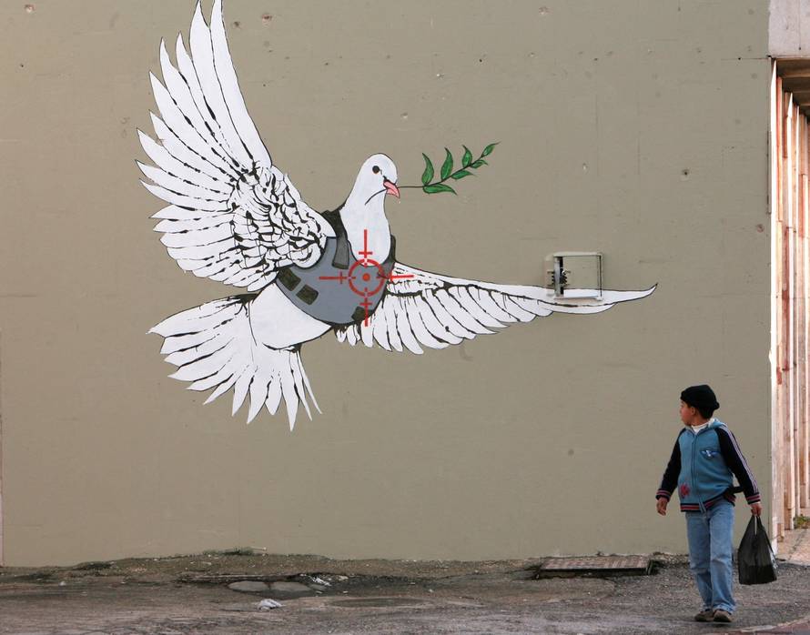 A Palestinian boy looks at one of six new images painted by British street artist Banksy as part of a Christmas exhibition in the West Bank town of Bethlehem