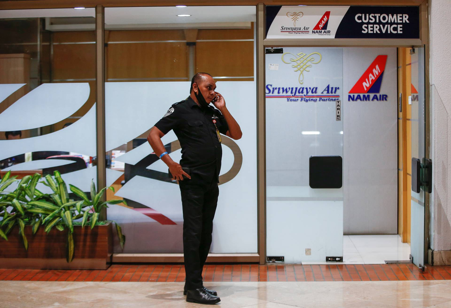 Aviation security officer uses a phone at Soekarno-Hatta International Airport in Tangerang