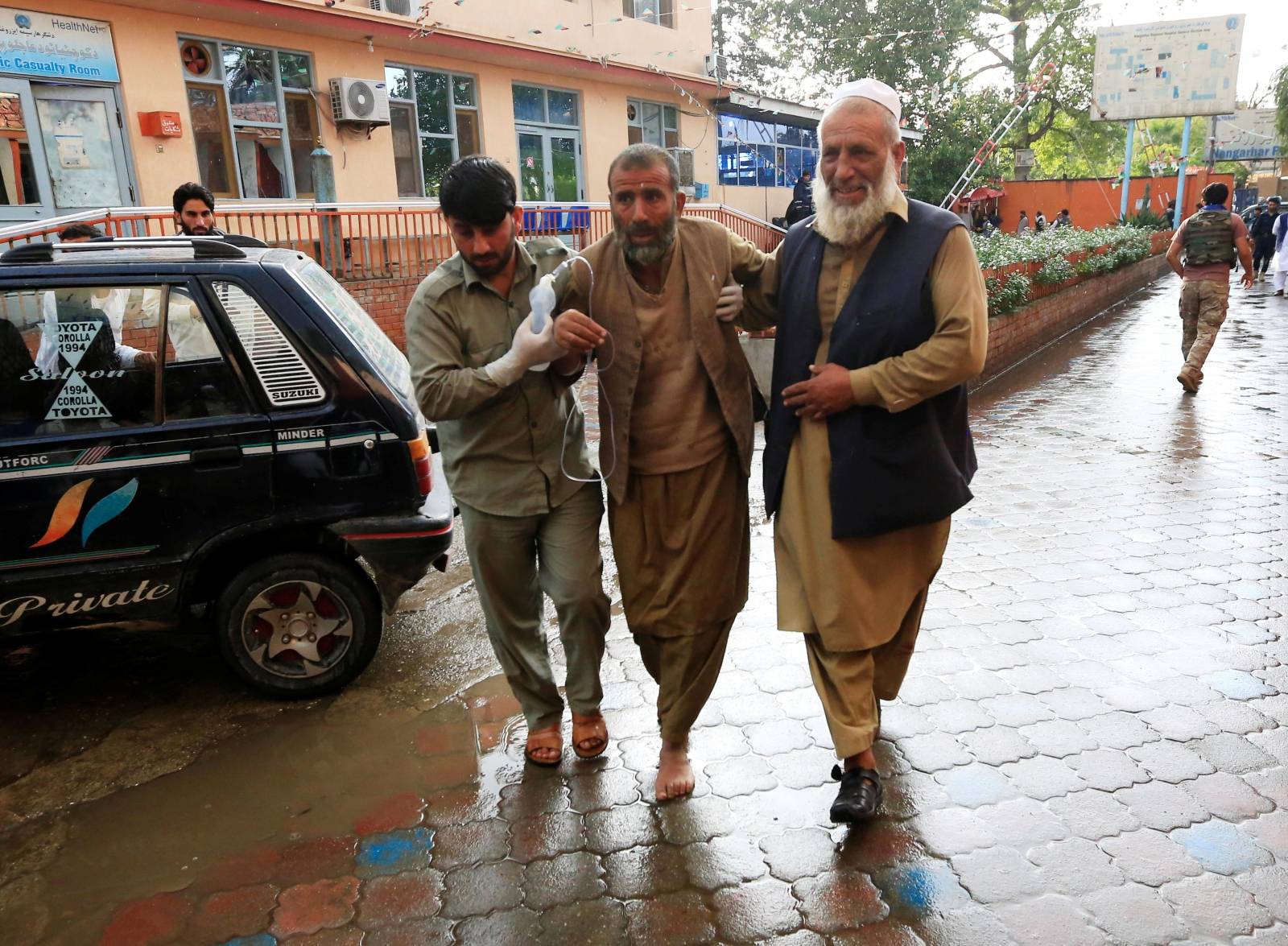 Men carry an injured person to a hospital after a bomb blast at a mosque, in Jalalabad, Afghanistan