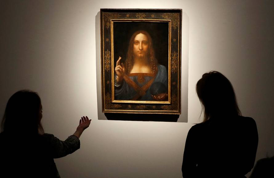 Members of Christie's staff pose for pictures next to Leonardo da Vinci's "Salvator Mundi" painting in London