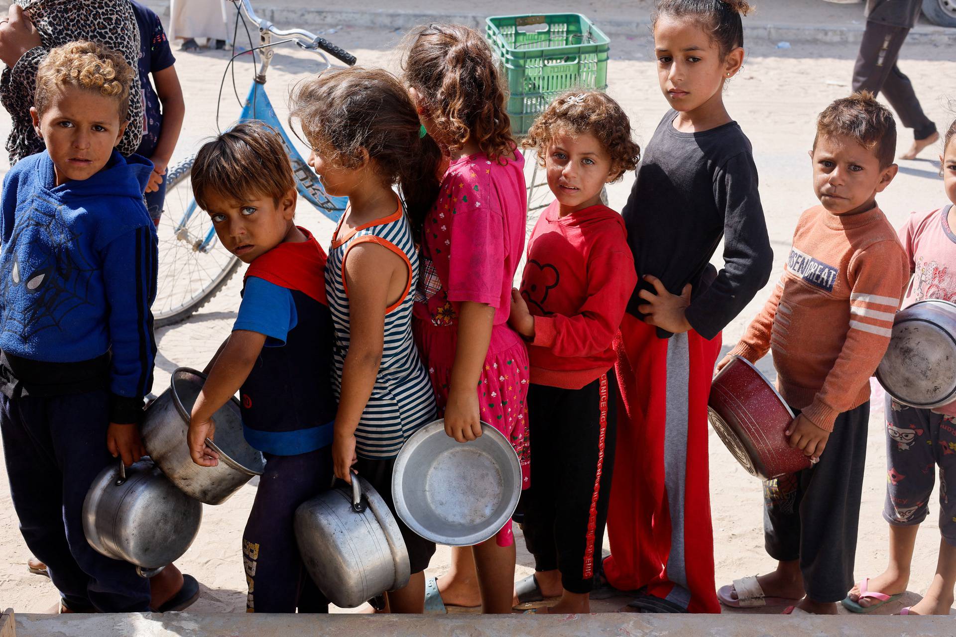 Palestinians gather to receive food cooked by a charity kitchen, in Khan Younis