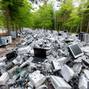 Electronic waste pile in forested area showcases environmental concern and recycling issues