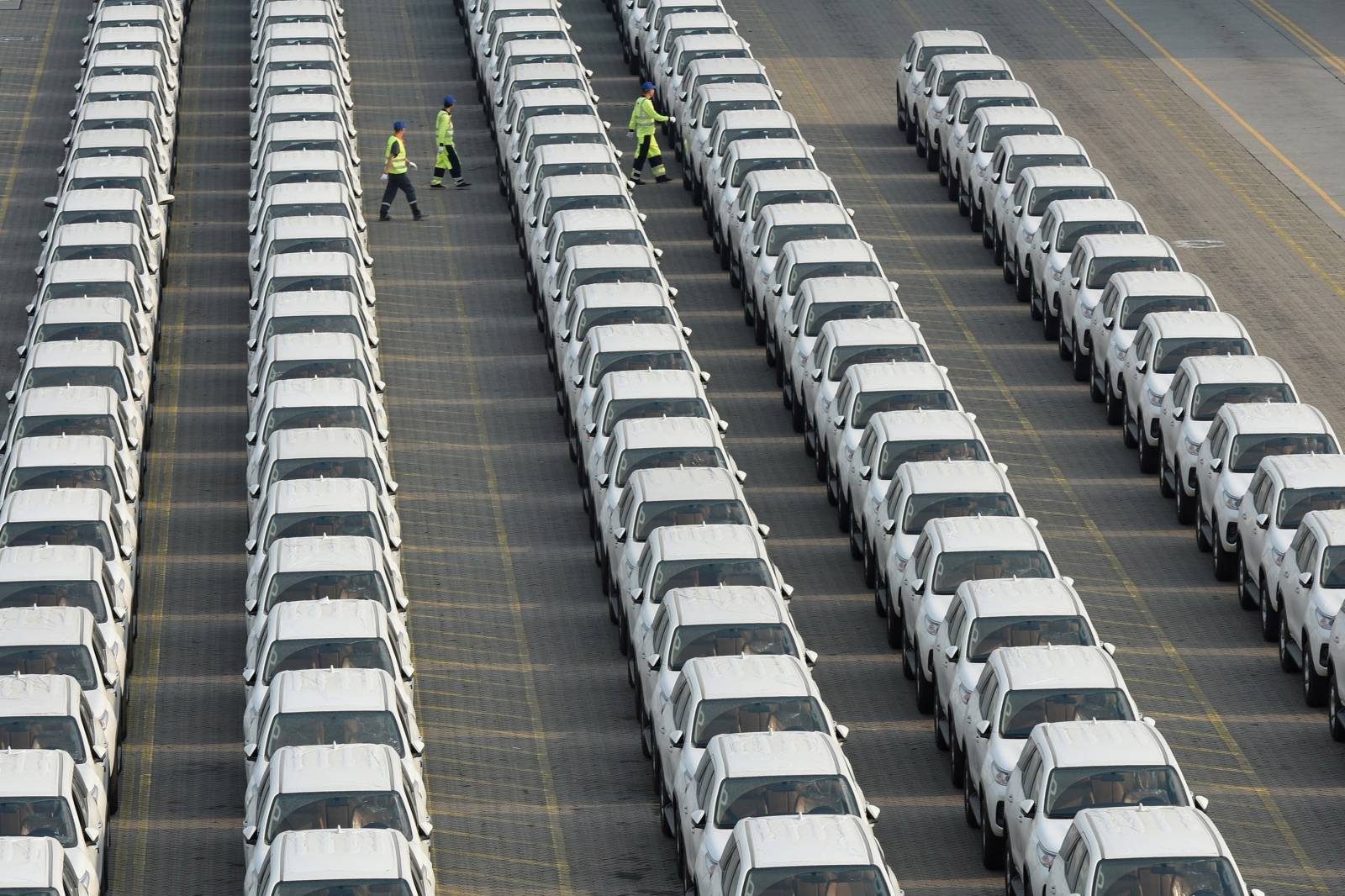 Workers walk among the newly arrived imported Toyota cars at the Shenzhen Dachan Bay Terminals in Guangdong