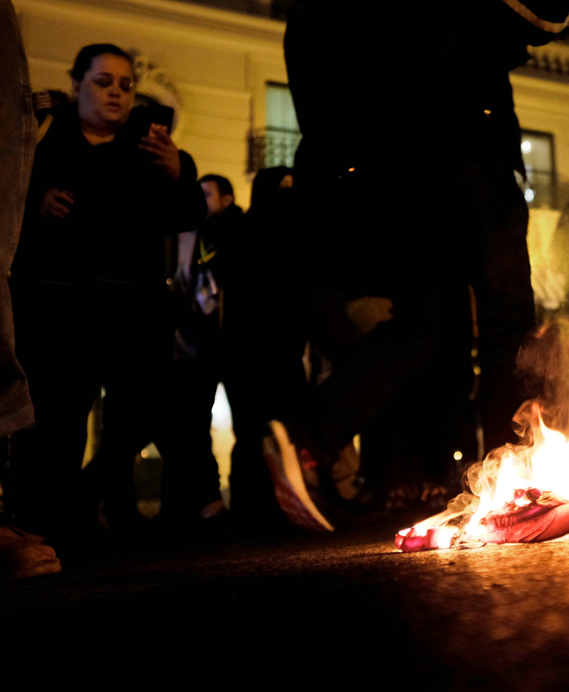 Demonstrators against U.S. President-elect Donald Trump burn a red "Make America Great Again" baseball cap as they march through the streets of downtown Washington