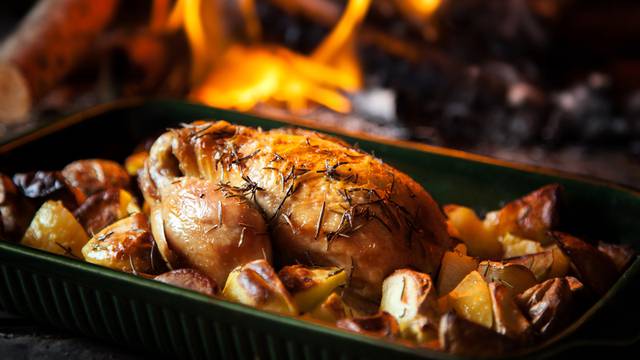 Roast chicken with potatoes with fiery background.