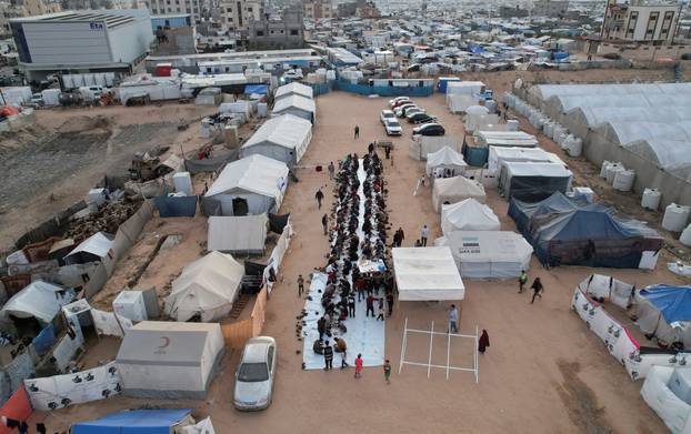 A drone view shows Palestinians, who were displaced by Israel's military offensive, gathering to have their Iftar (breaking of the fast) during the holy month of Ramadan, in Rafah in the southern Gaza Strip