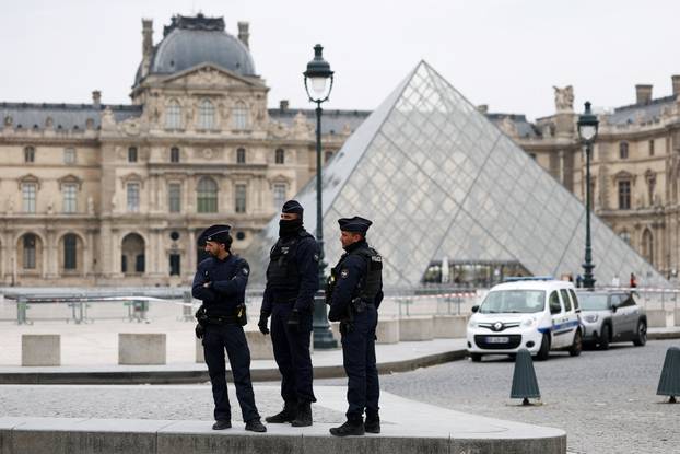 Police stand near the pyramid of the Louvre museum after reports of a robbery, in Paris
