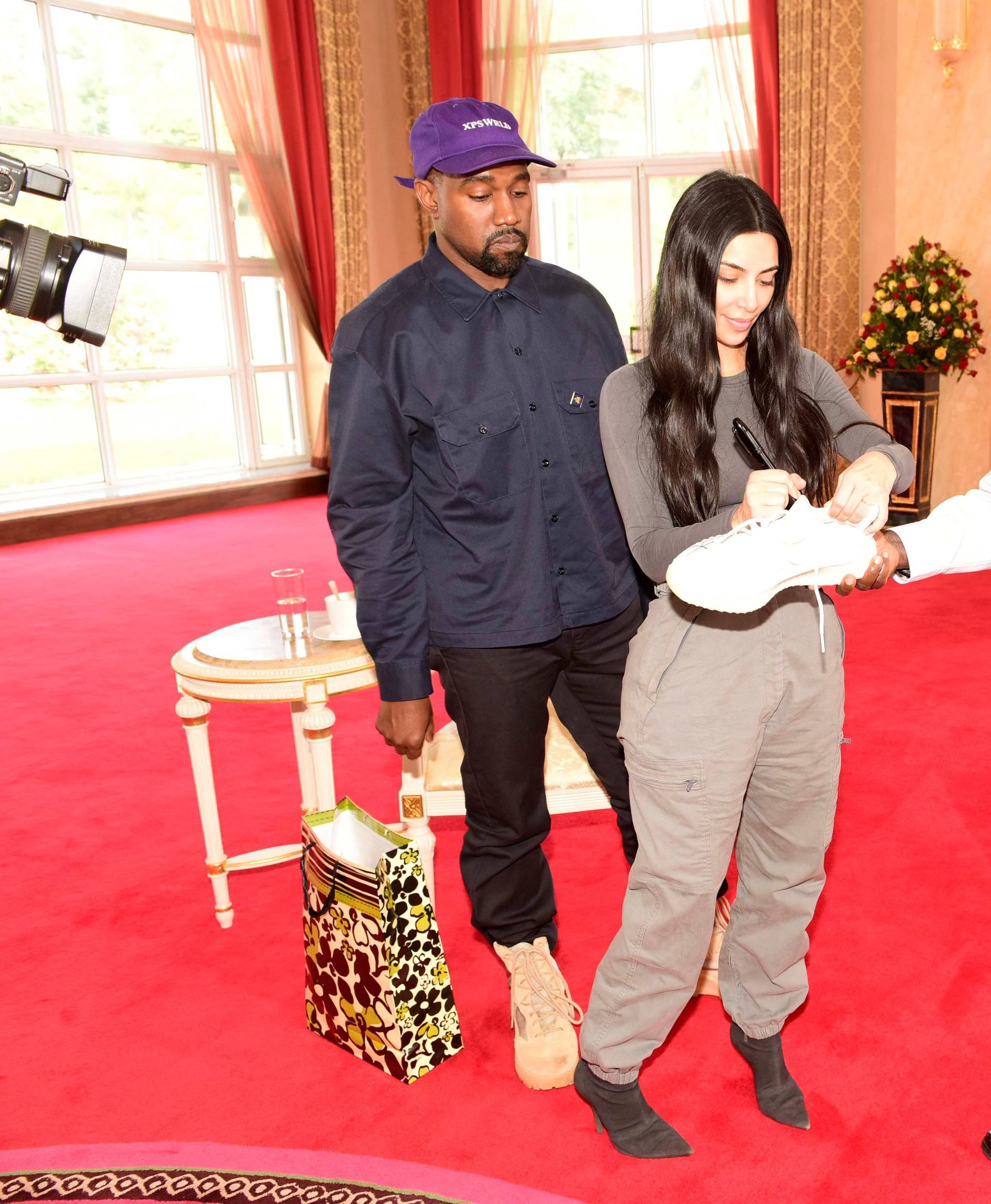 Kim Kardashian autographs a shoe for Uganda's President Yoweri Museveni as Rapper Kanye West looks on when they paid a courtesy call at State House, Entebbe
