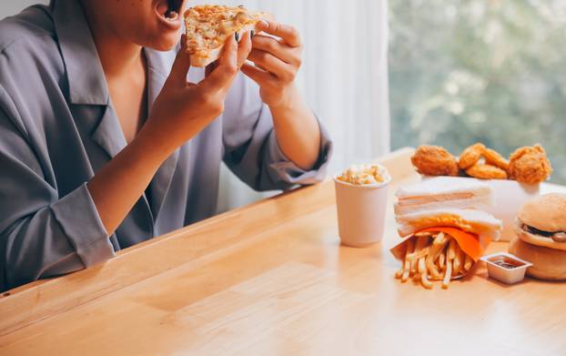 Cropped image of woman holding pizza slice at restaurant