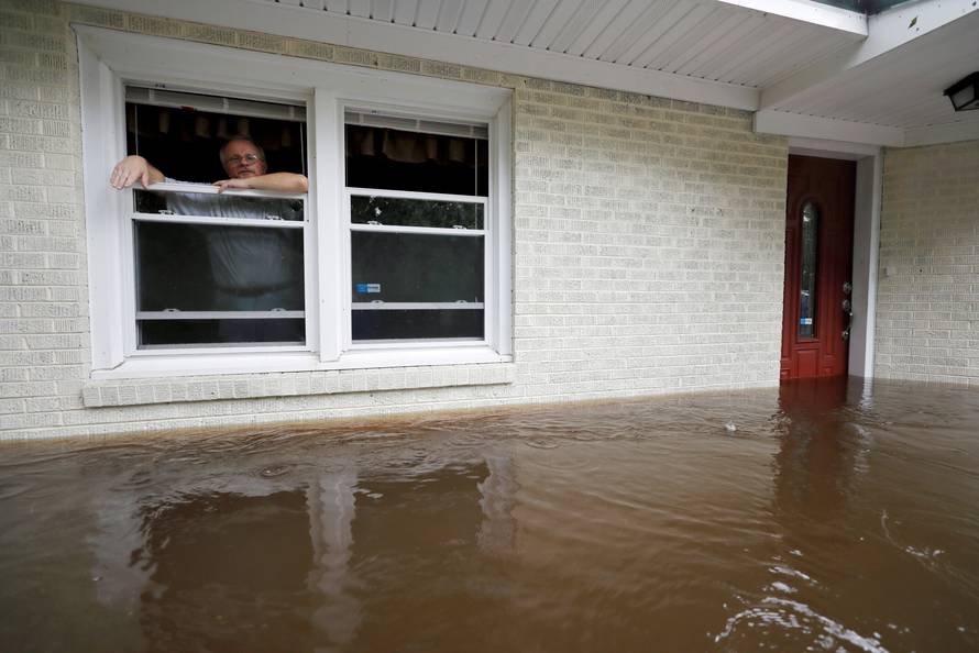 Gavrilovic peers out the window of his flooded home while considering whether to leave with his wife and pets as waters rise in North Carolina