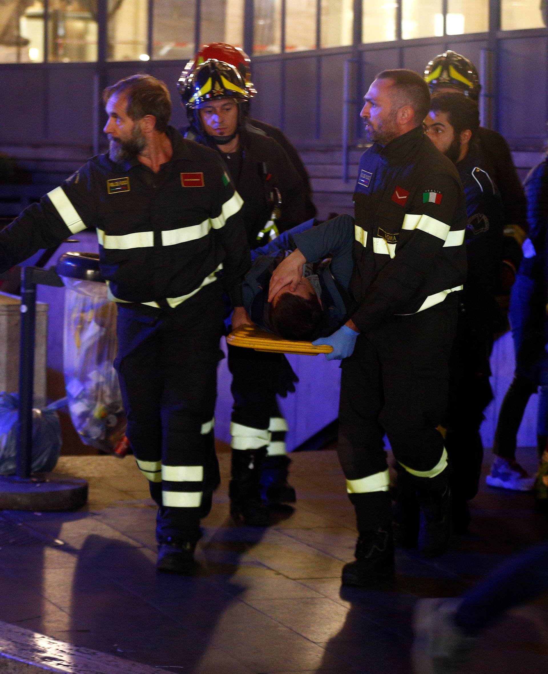 Fire fighters carry an injured person outside the underground where some of CSKA Moscow supporters were injured in Rome