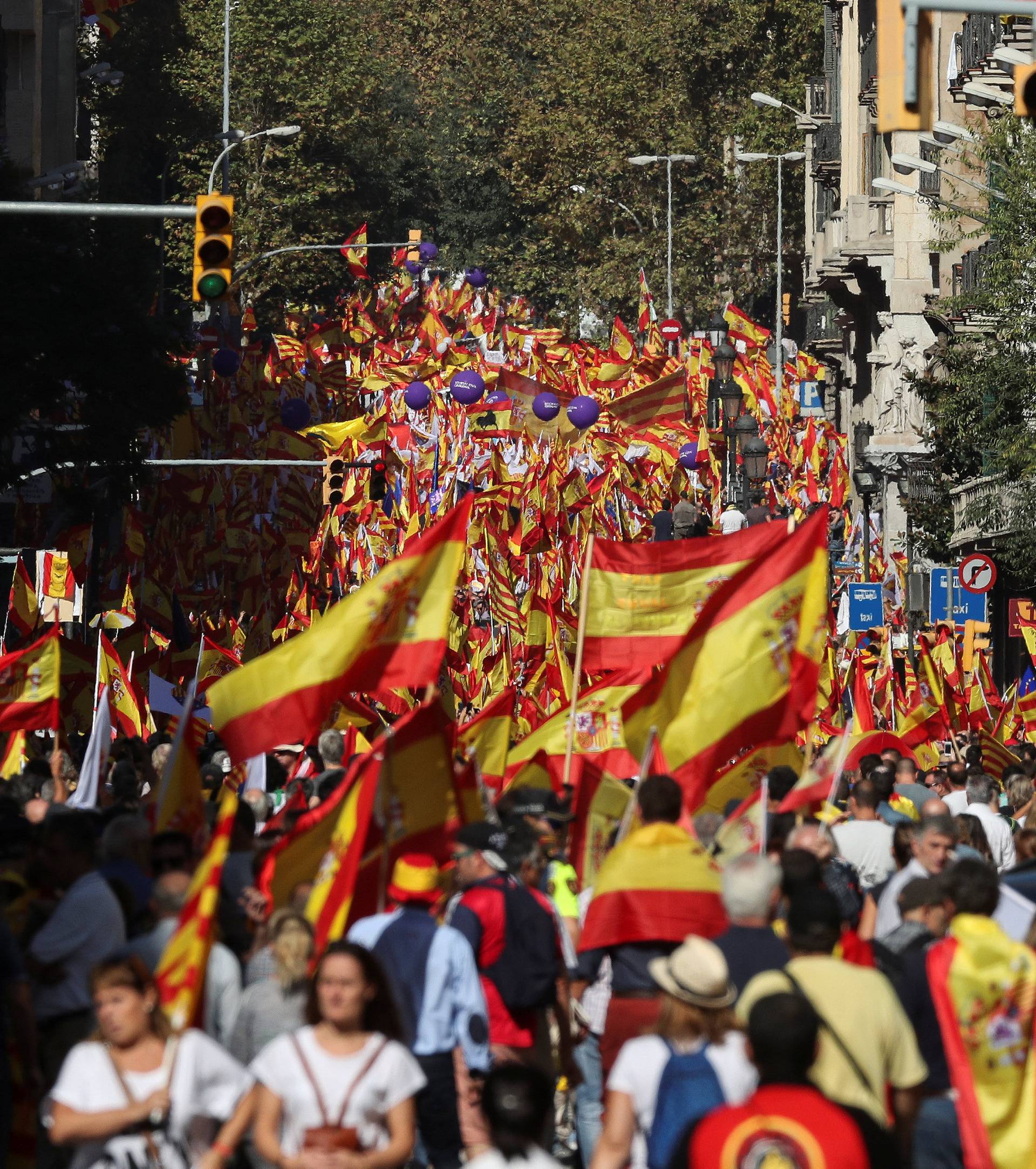 People wave Spanish and Catalan flags as they attend a pro-union demonstration organised by the Catalan Civil Society organisation in Barcelona