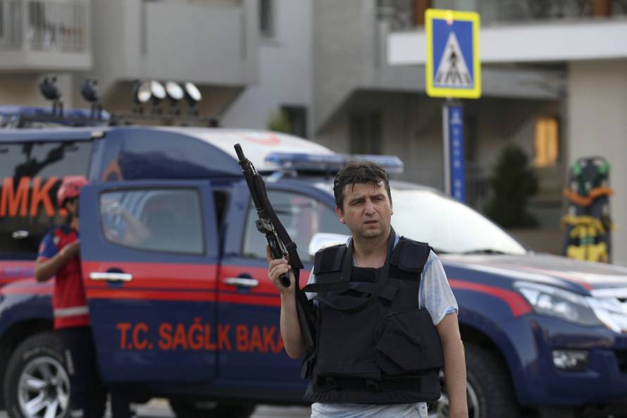 A plain clothes policeman holds a weapon in front of a police vehicle in the resort town of Marmaris