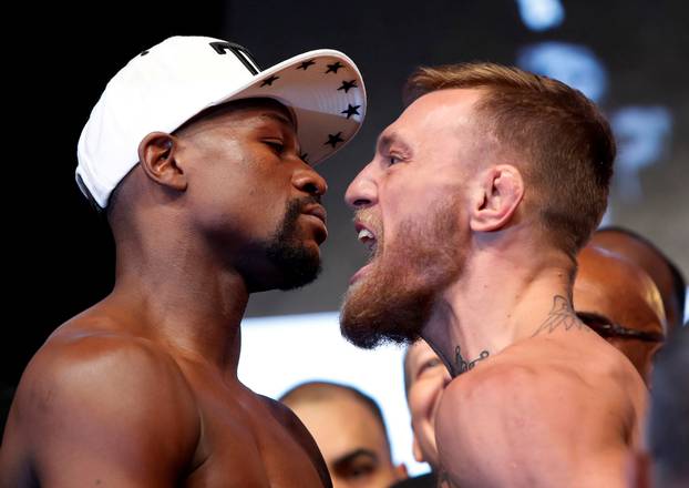 Undefeated boxer Floyd Mayweather Jr. (L) of the U.S. and UFC lightweight champion Conor McGregor of Ireland face off during their official weigh-in at T-Mobile Arena in Las Vegas