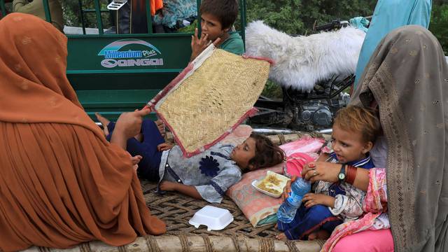 Women and children sit outside their tent, after taking refuge on a motorway, following rains and floods during the monsoon season in Charsadda