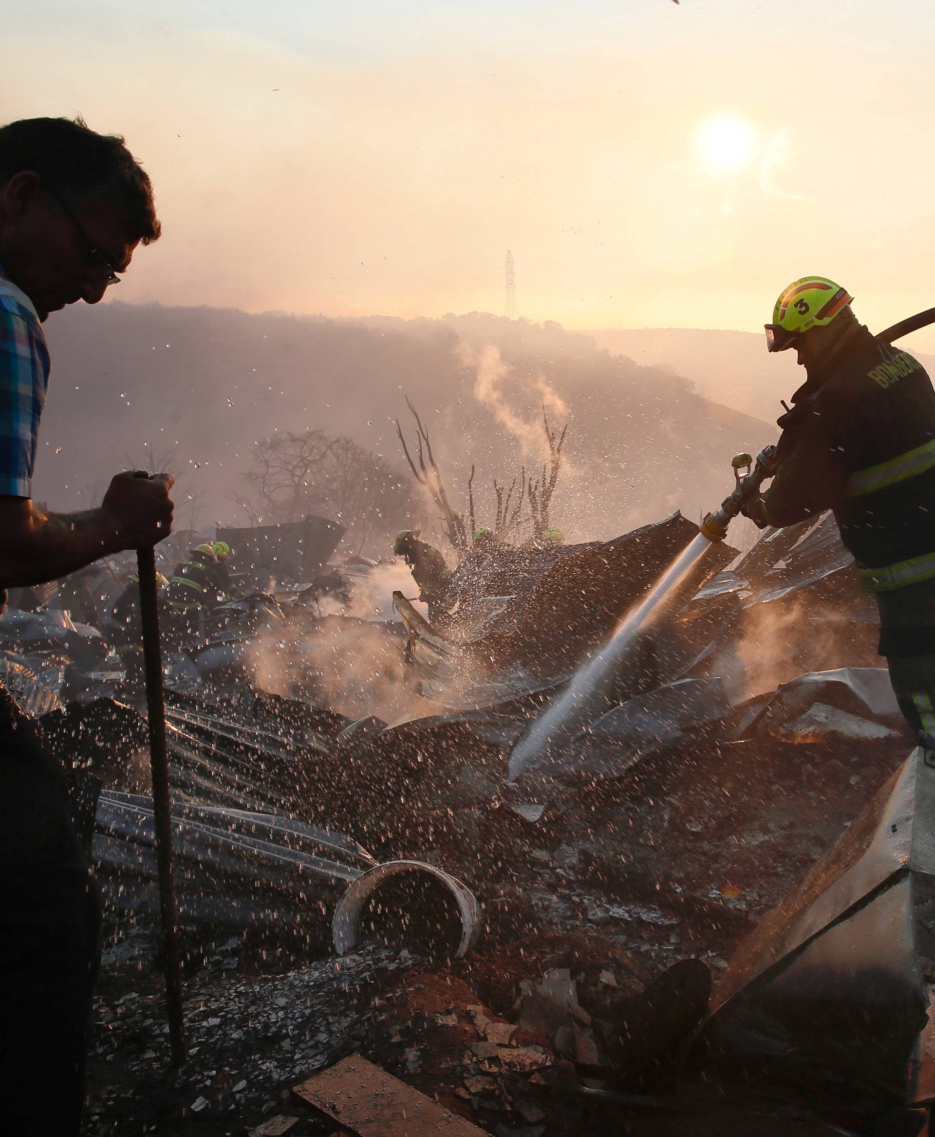 Firefighters work to put out a fire in a house on a hill, where more than 100 homes were burned due to a forest fire but there have been no reports of death, local authorities said in Valparaiso, Chile