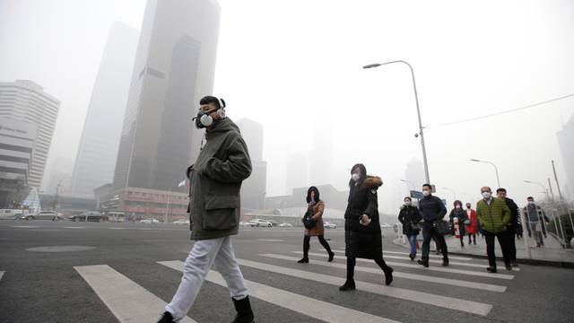 A man wearing a respiratory protection mask walks toward an office building during smog in Beijing