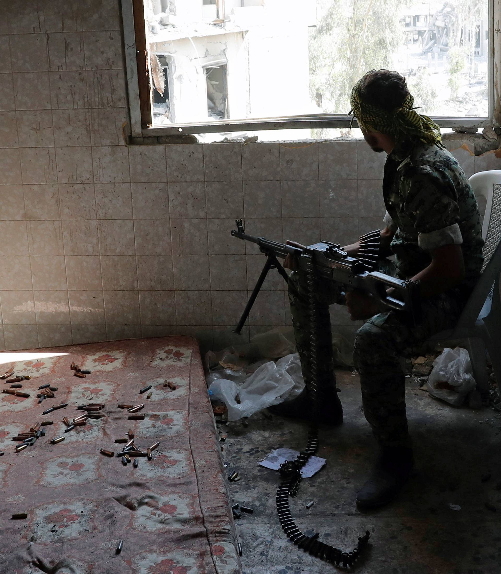 A fighter of Syrian Democratic Forces takes up a position inside a building at the frontline in Raqqa