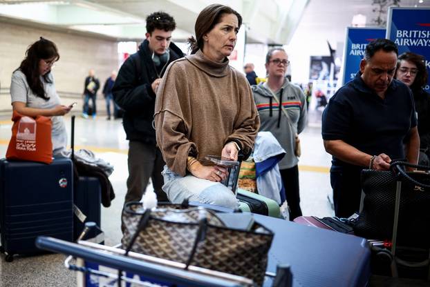 Passengers wait at Fiumicino Airport, after fire at an electrical substation wiped out power at Heathrow International Airport
