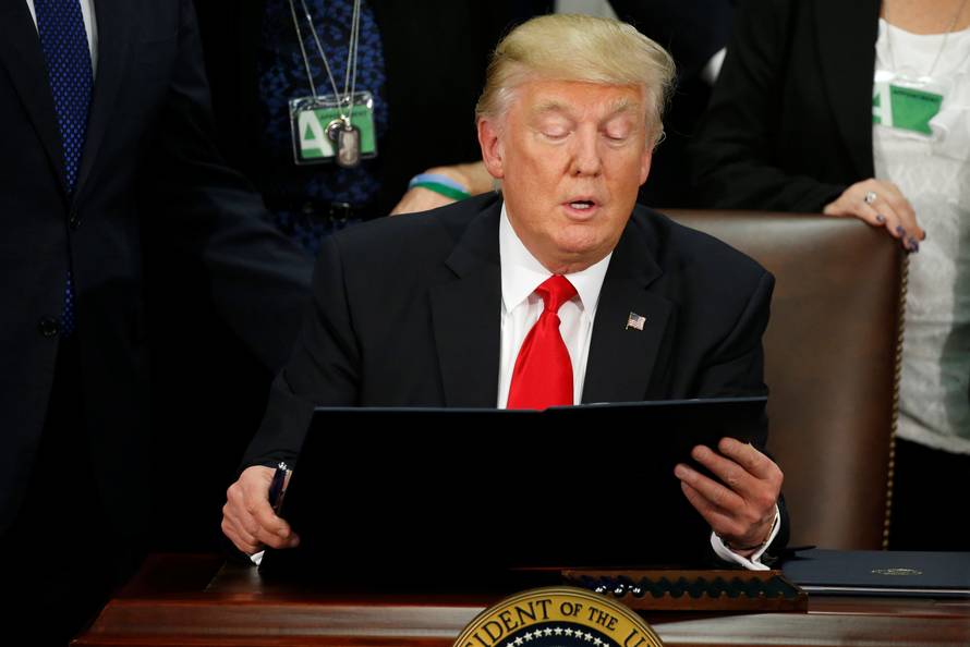 U.S. President Trump reads an executive order before signing it at Homeland Security headquarters in Washington