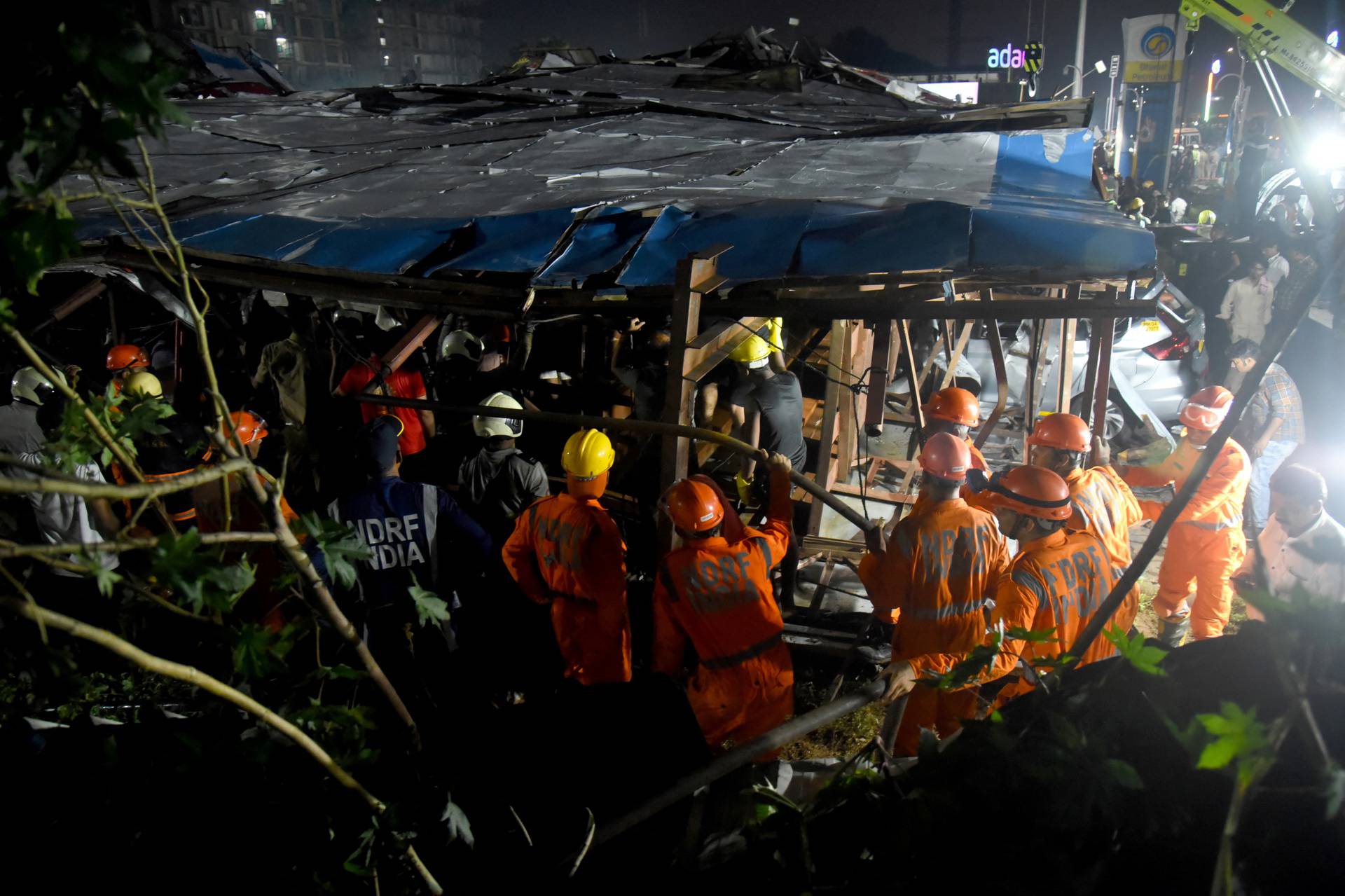 Members of rescue teams search for survivors amidst the debris after a massive billboard fell during a rainstorm in Mumbai