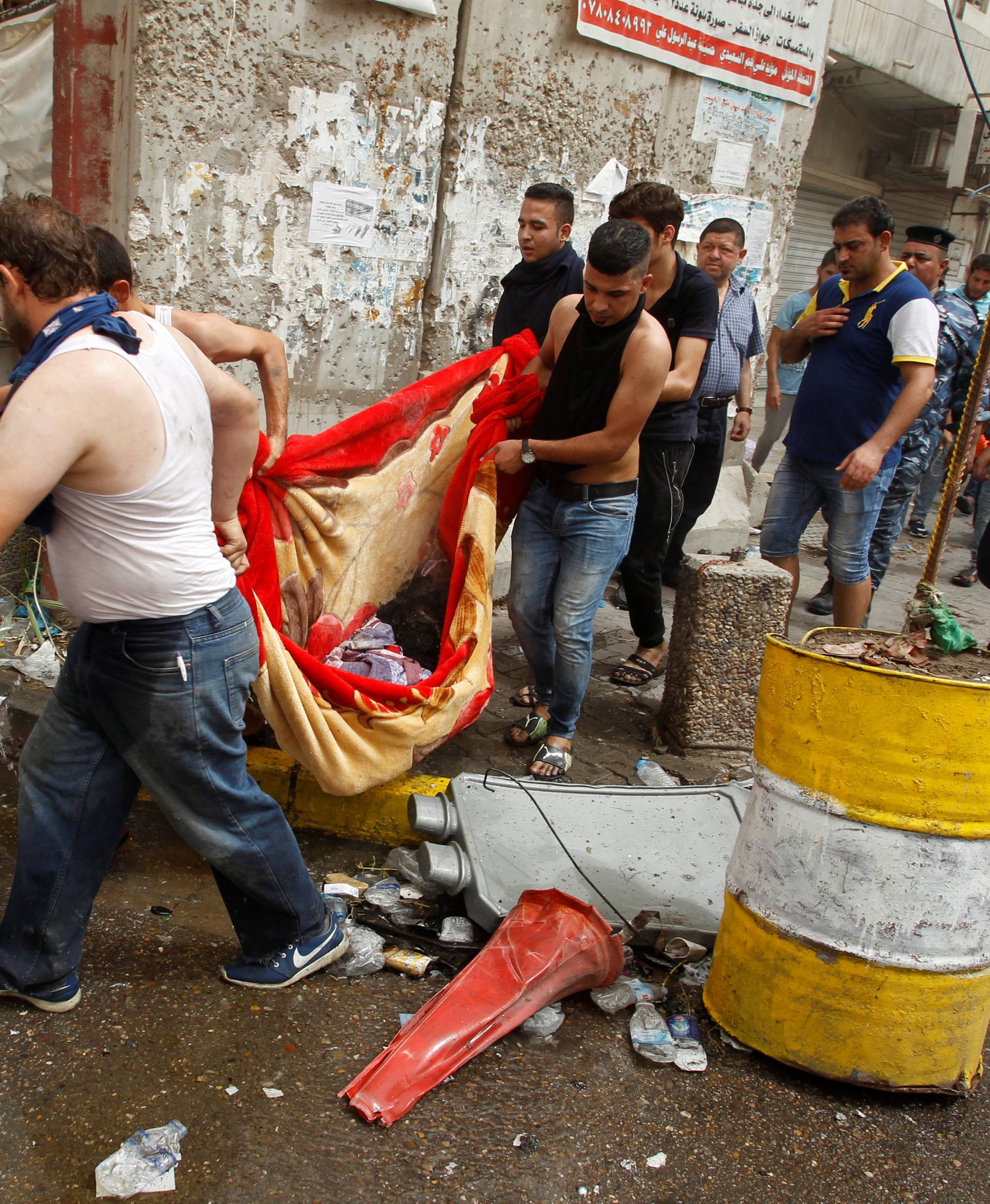 Civilians carry the body of a victim killed in a suicide car bomb in the Karrada shopping area, in Baghdad, Iraq 