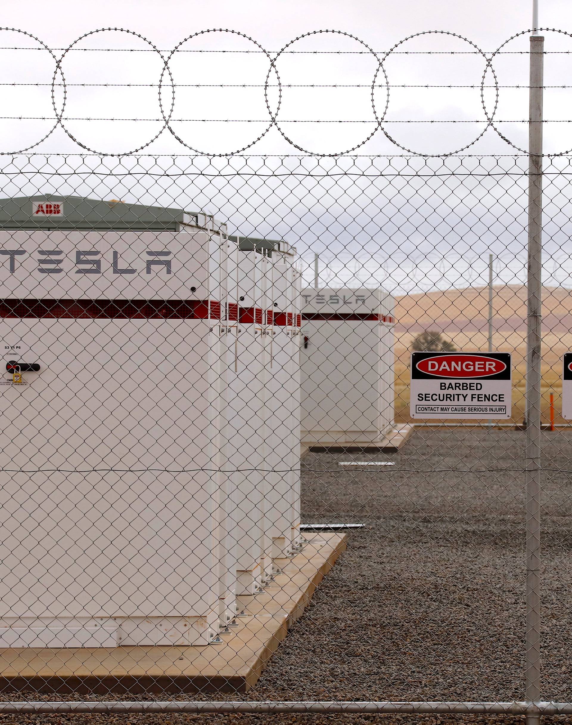 Warning signs adorn the fence surrounding the compound housing the Hornsdale Power Reserve, featuring the world's largest lithium ion battery made by Tesla, during the official launch near the South Australian town of Jamestown