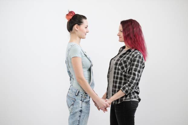 Two girls hug on a white background. Homosexual lesbian couple. Casual clothes.