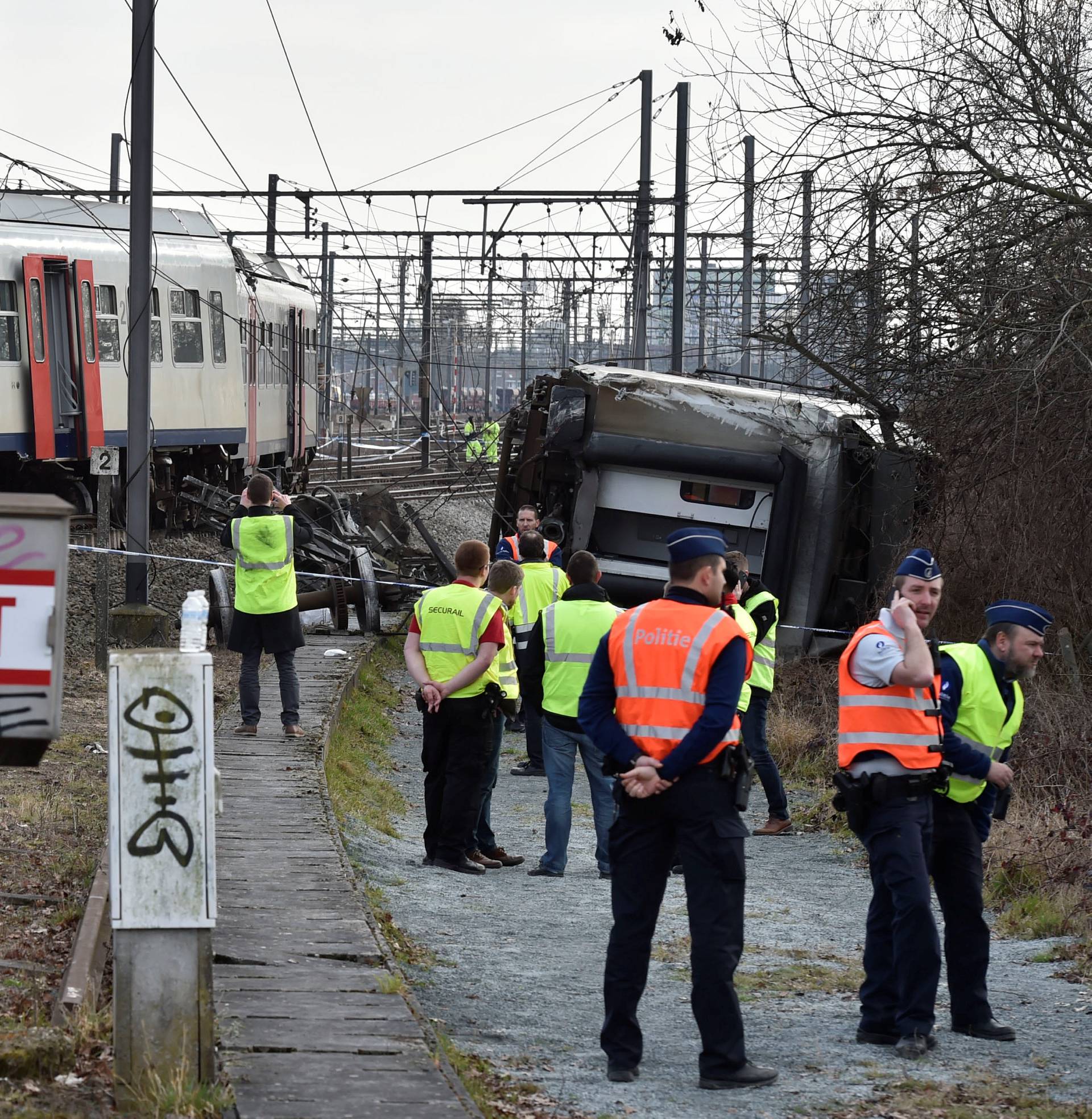 Rescuers and police officers stand next to the wreckage of a passenger train after it derailed in Kessel-Lo near Leuven