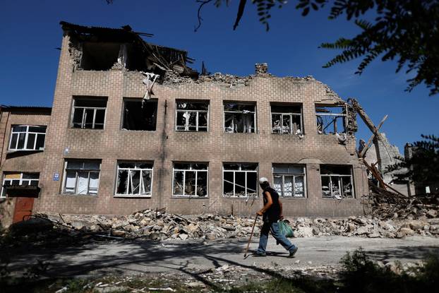 A man walks near a destroyed school, as Russia's attack on Ukraine continues, in Toretsk