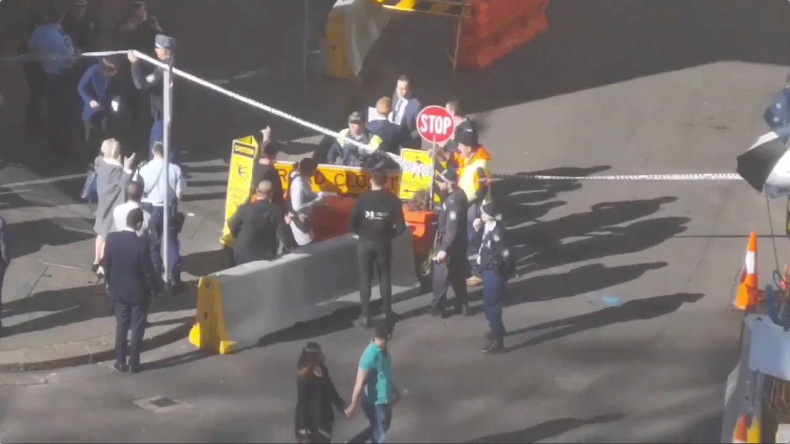 People walk past security officers standing around a barricaded area in Sydney