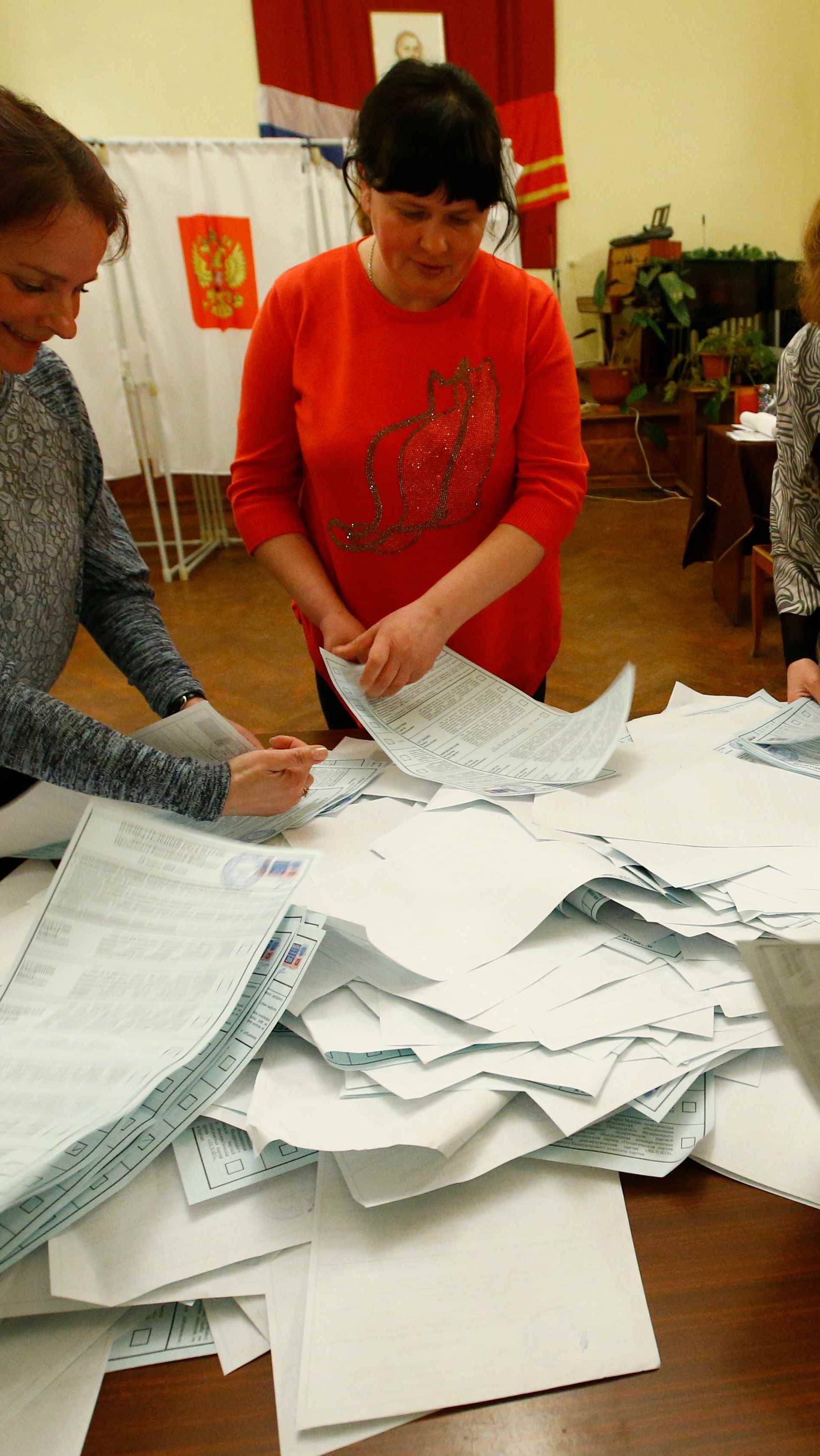 Members of a local election commission sort ballots before starting to count votes during the presidential election at a polling station in a settlement in Smolensk Region