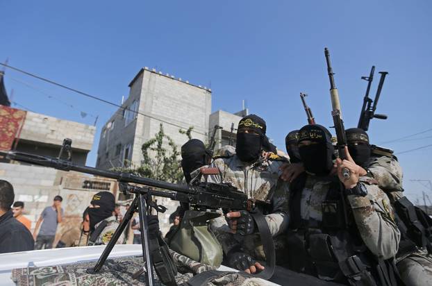 Palestinian Islamic Jihad militants ride on a pickup truck during the funeral of their comrade in the southern Gaza Strip